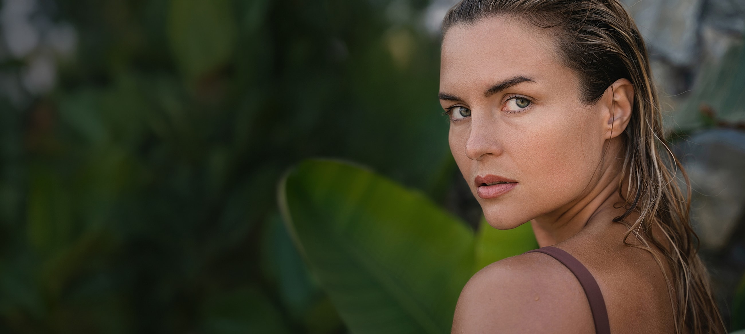 Woman with wet hair against green background.