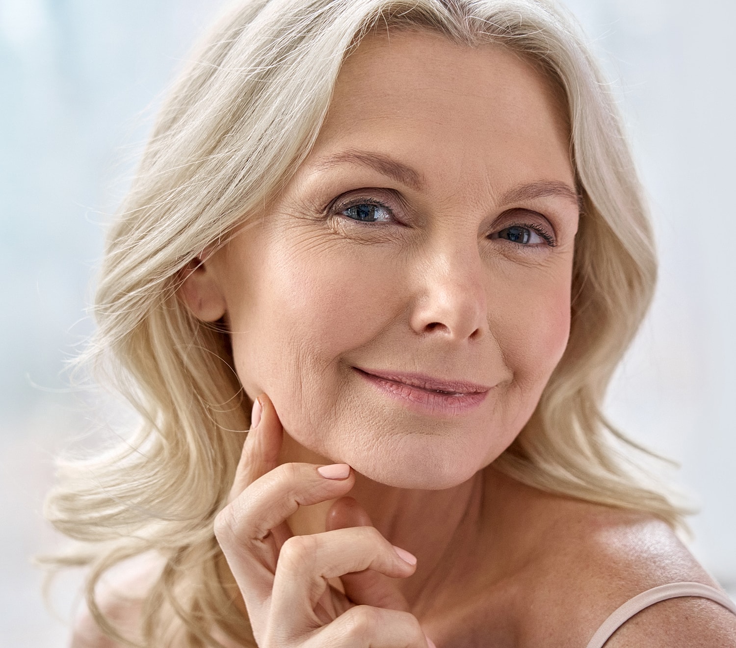 Smiling woman with long blonde hair, softly lit.