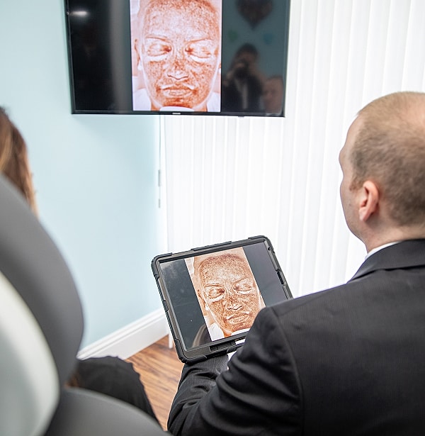 Patient reviewing facial imaging on digital devices.