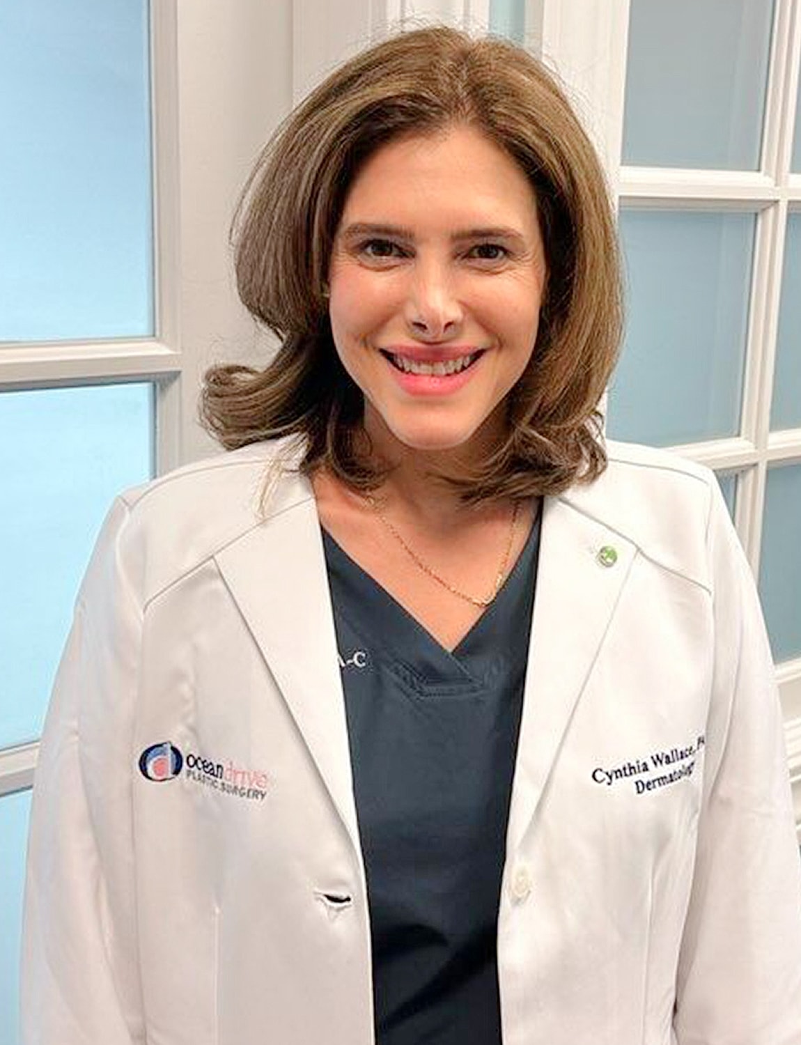 Female dermatologist smiling in medical attire.