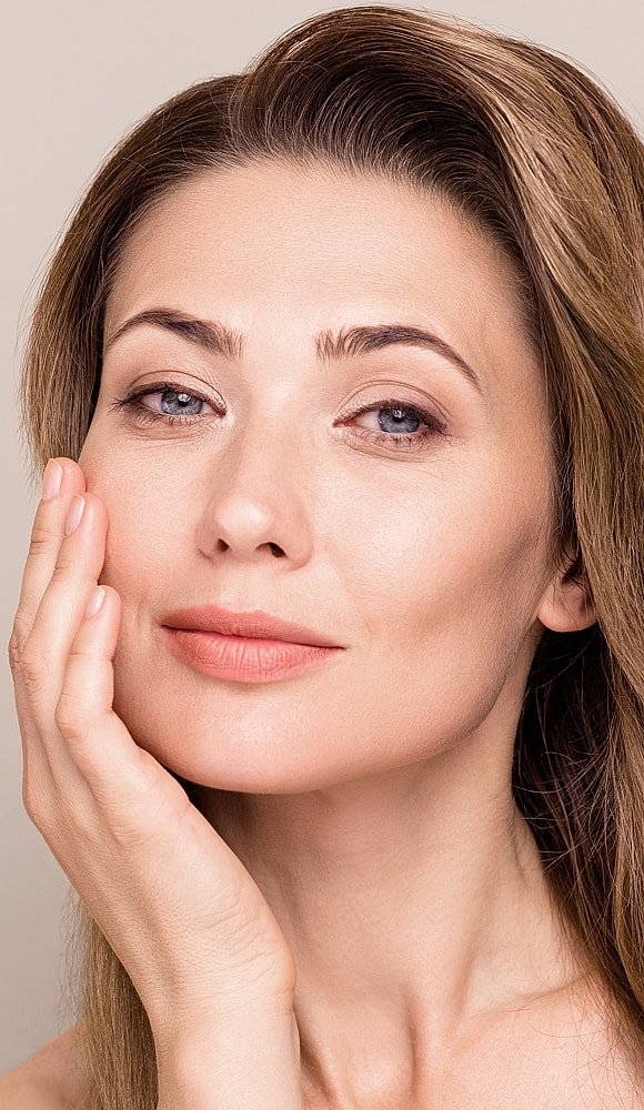 Woman softly touching her face, serene expression.