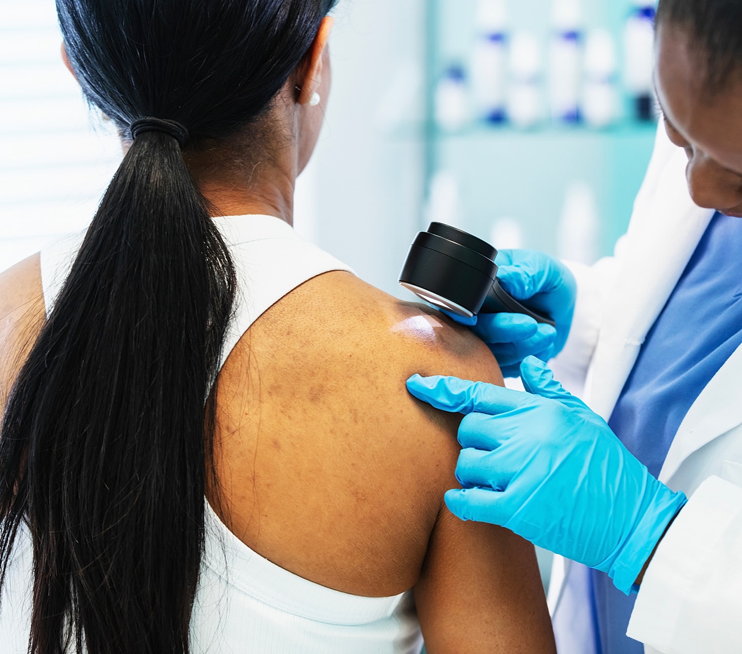 Doctor examining patient's shoulder with magnifying glass.