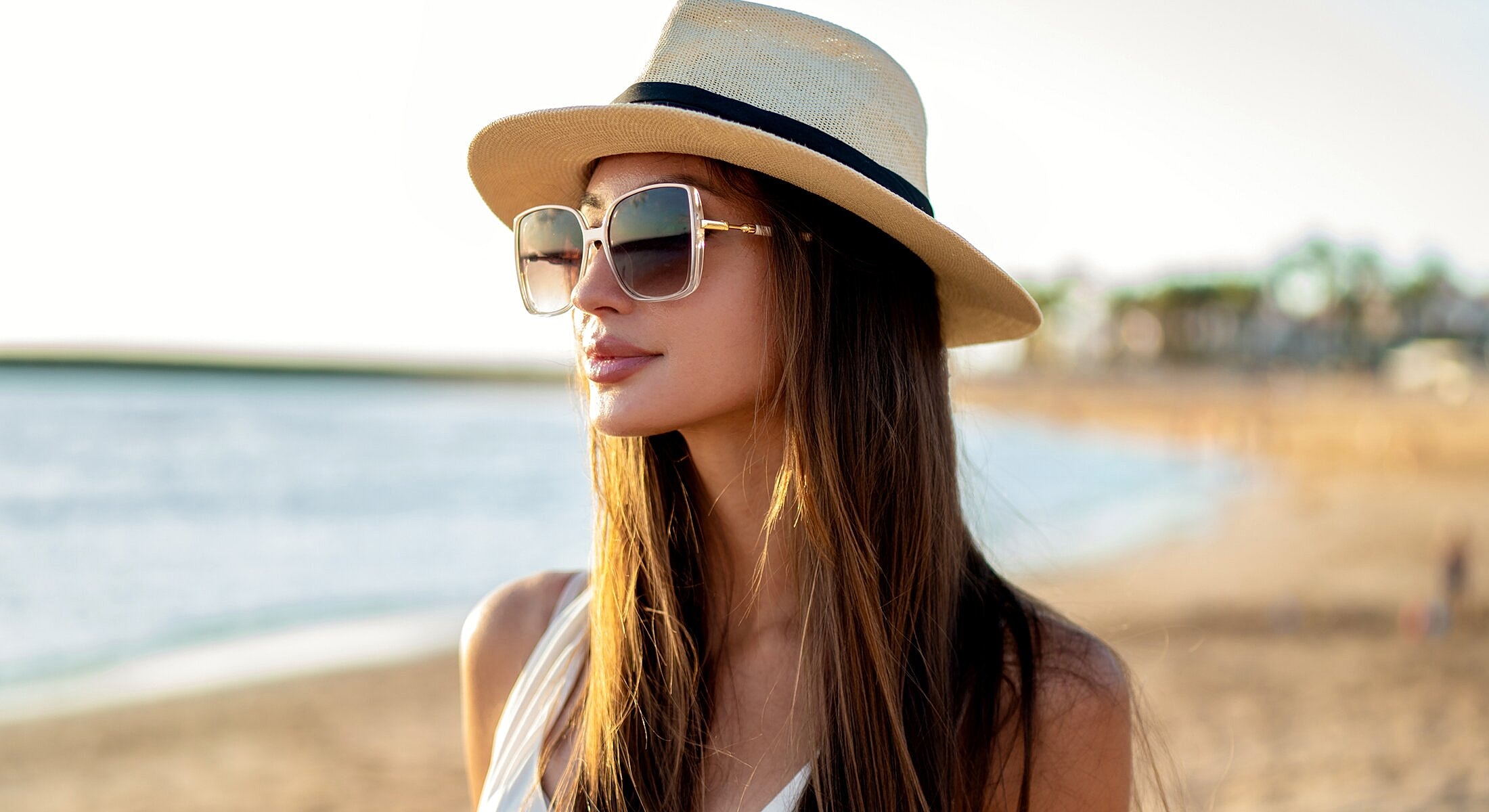 Woman in sunglasses and hat at the beach.