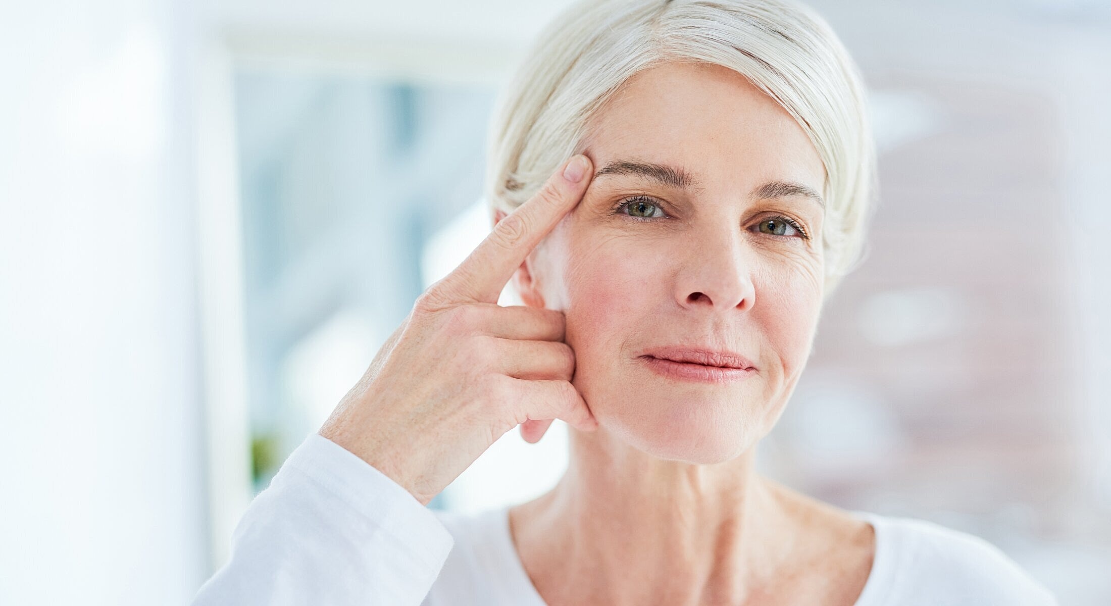 Woman touching her forehead with a thoughtful expression.